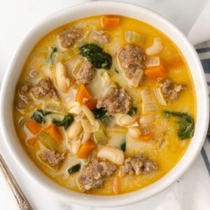 A bowl of white bean soup with Italian sausage, carrots and spinach.