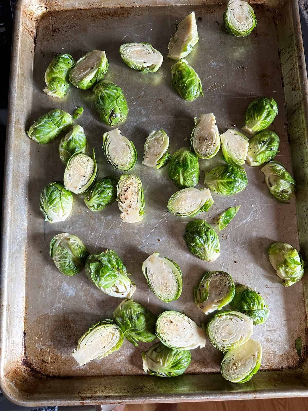Uncooked Brussels sprouts on a heated sheet pan.
