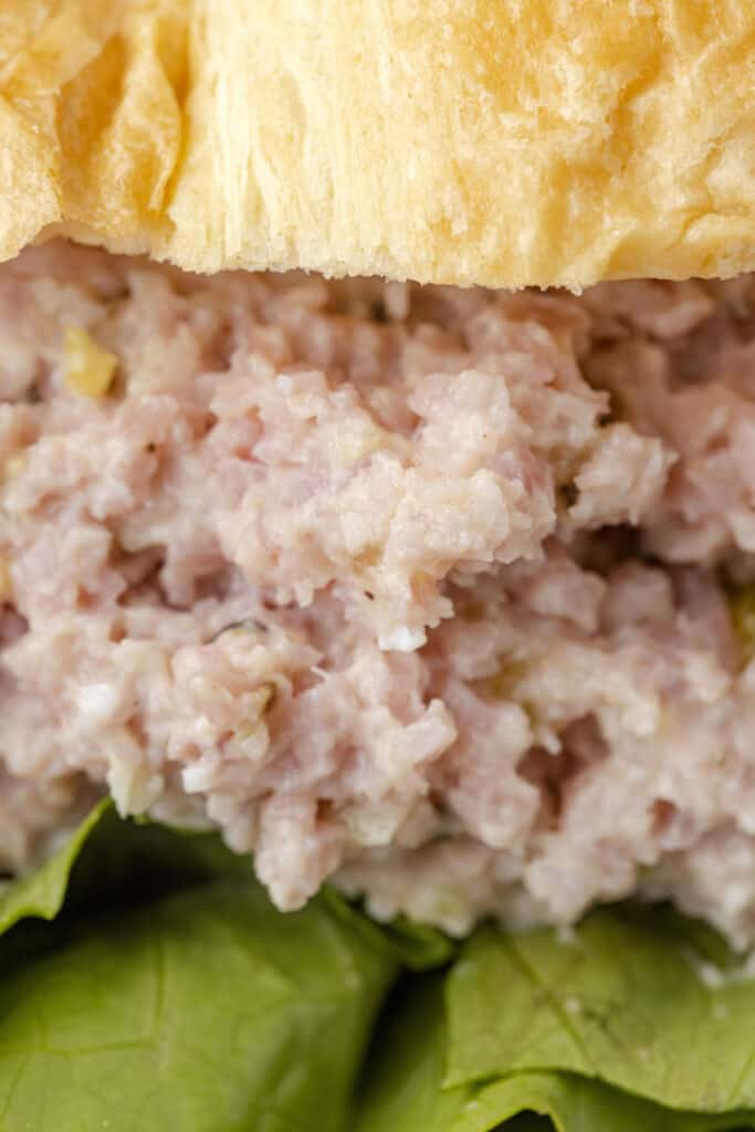 A close up of ham salad on a sandwich.