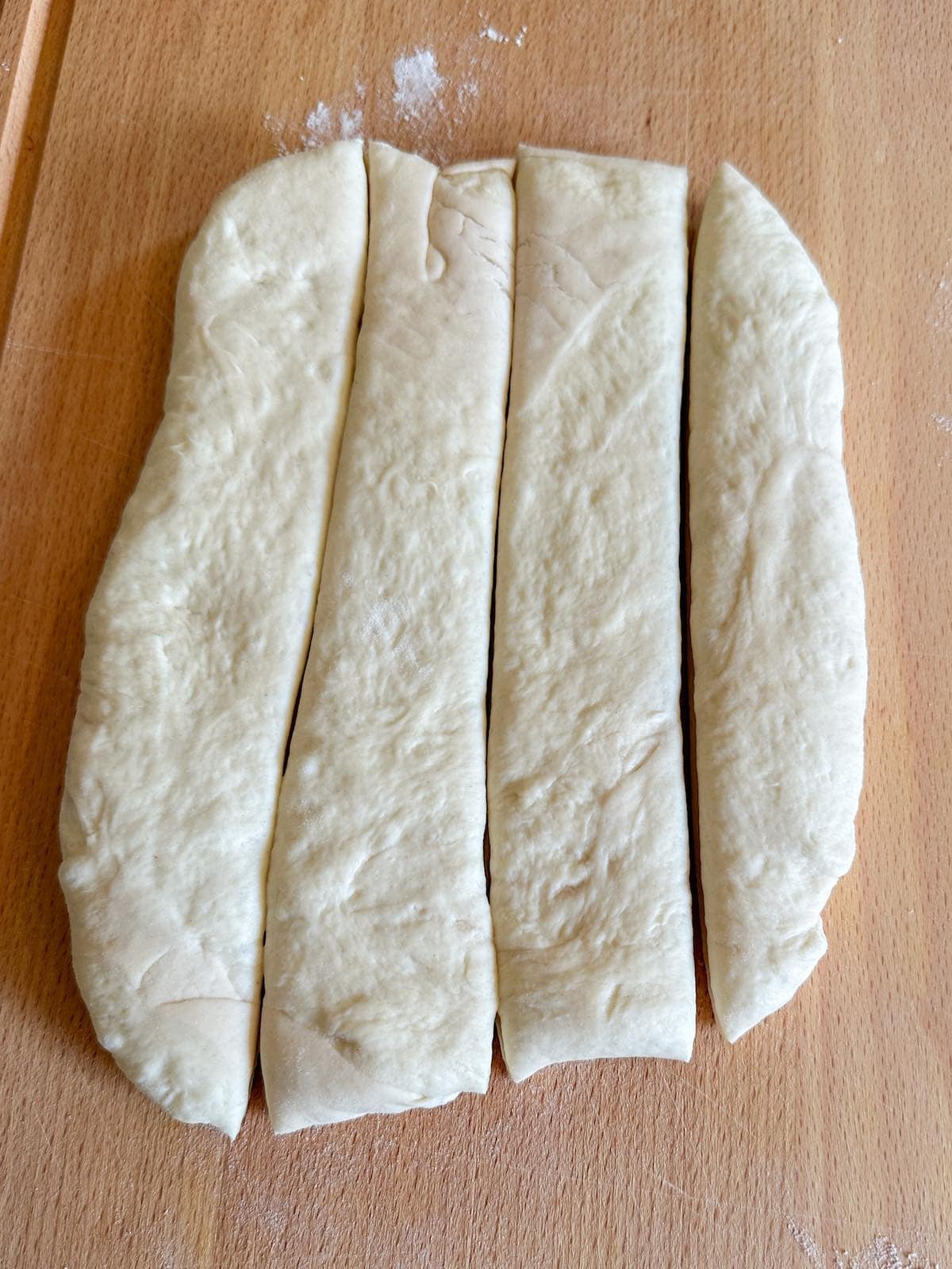 Pizza dough rolled into a rectangle shape and cut into four strips.