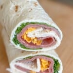 A flour tortilla with deli roast beef, cheese, and lettuce rolled up.