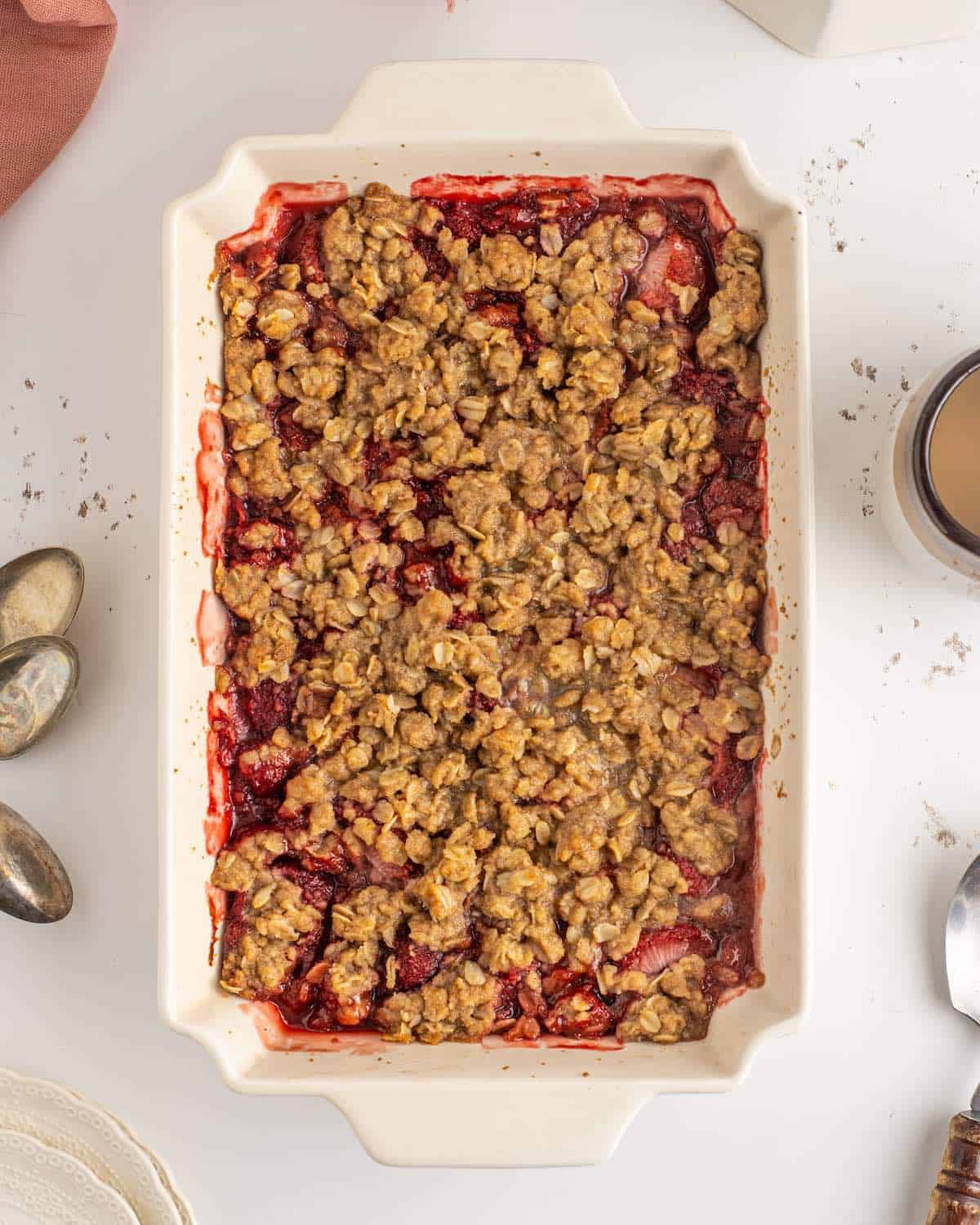 A baked dish of strawberry crumble on a kitchen countertop.