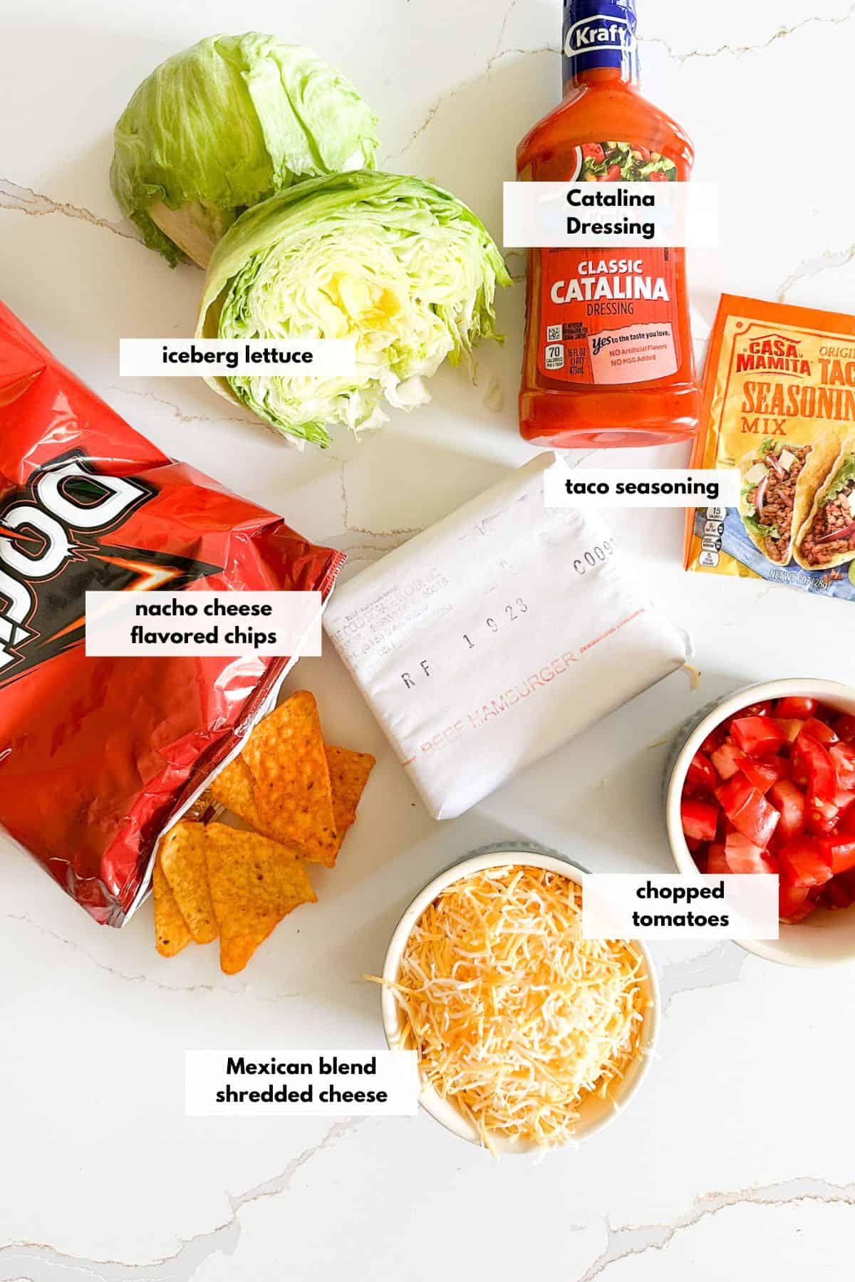 Ingredients to make this taco salad are catalina dressing, shredded cheese, chopped tomatoes, taco seasoning, iceberg lettuce and ground beef.
