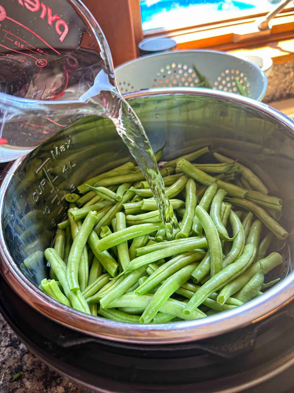 Water being poured onto a pot of trimmed green beans.