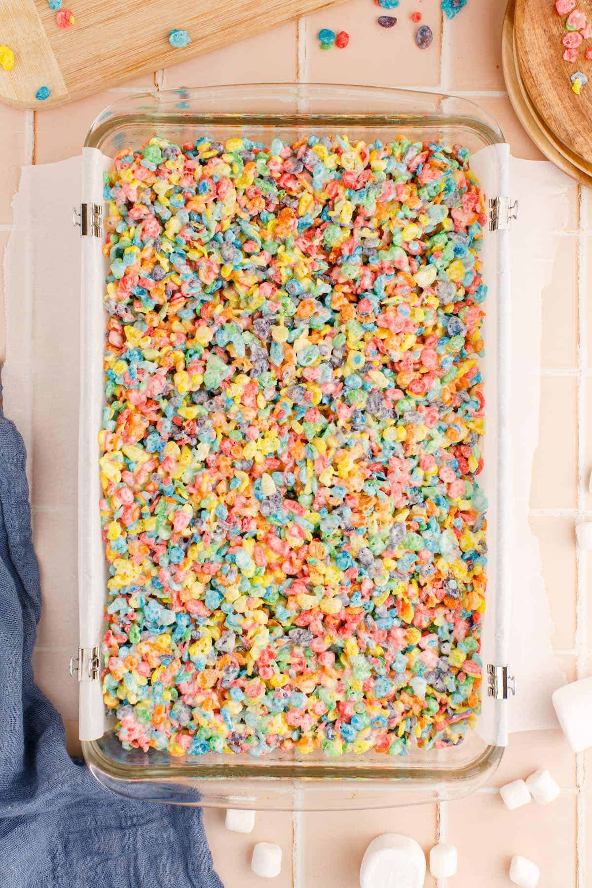 Fruity Pebbles treats cooling in 9x13 pan lined with parchment paper.