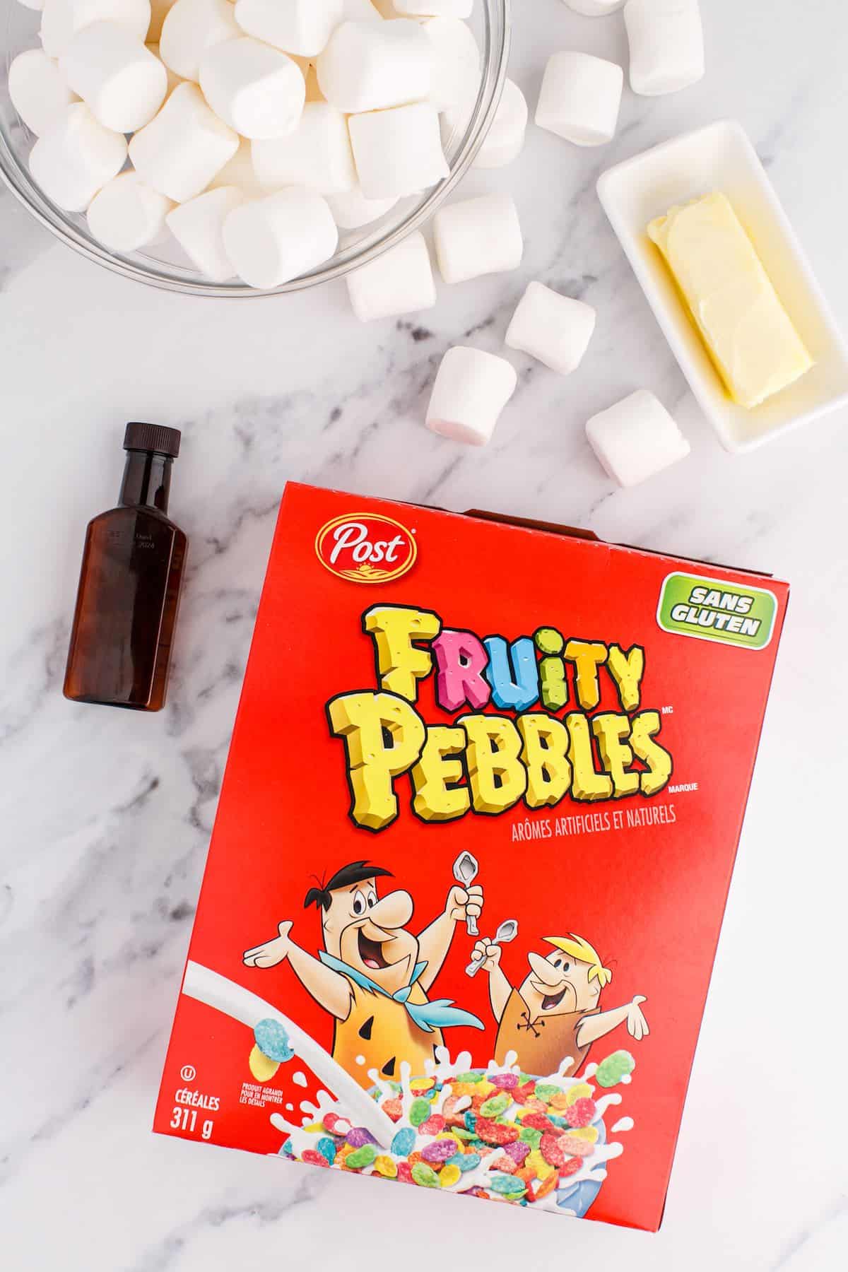 Fruity pebbles, marshmallows, butter and vanilla extract on a countertop.