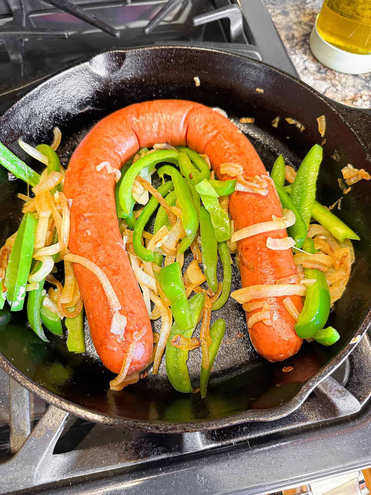 Kielbasa sausage with peppers and onions in a pan.