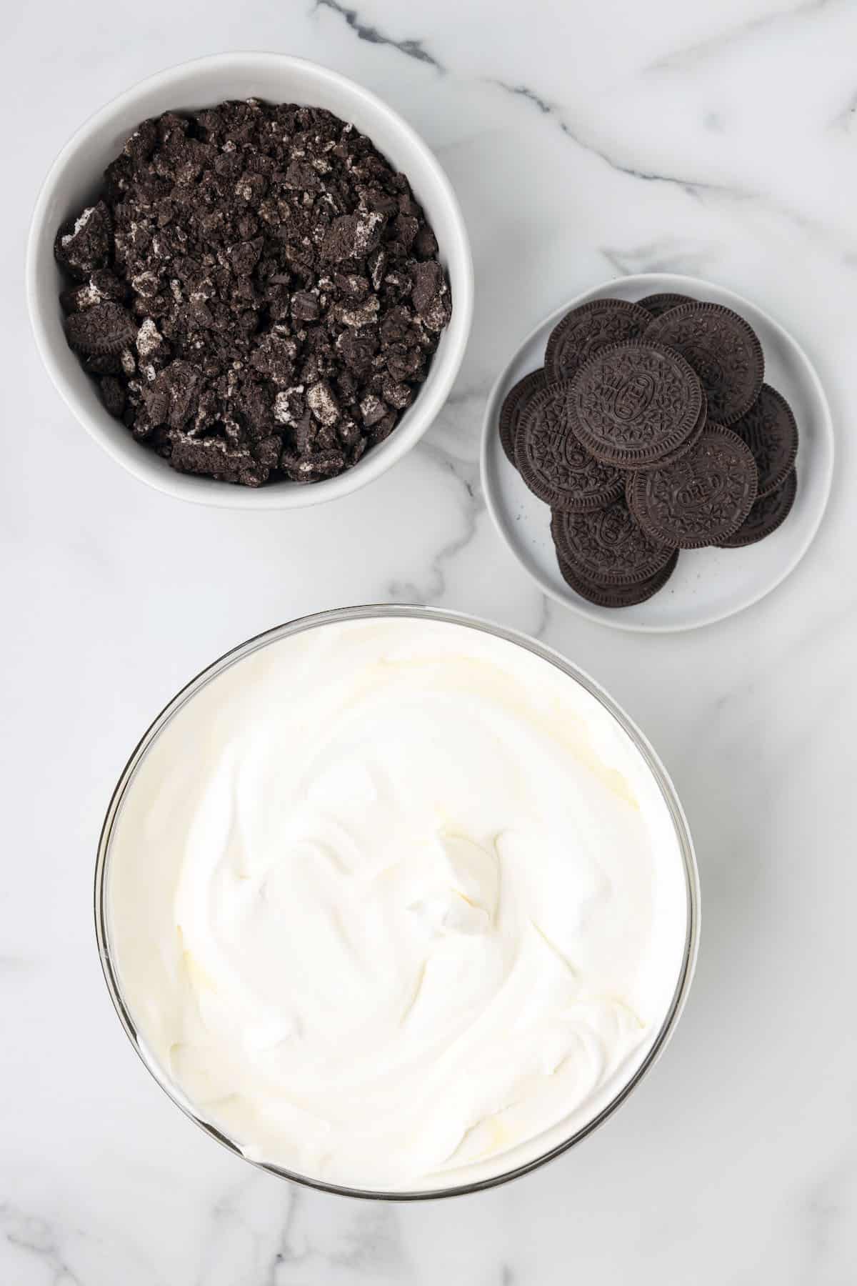 Fluffy and creamy pudding mixture in a bowl surrounded by chocolate oreo cookies.