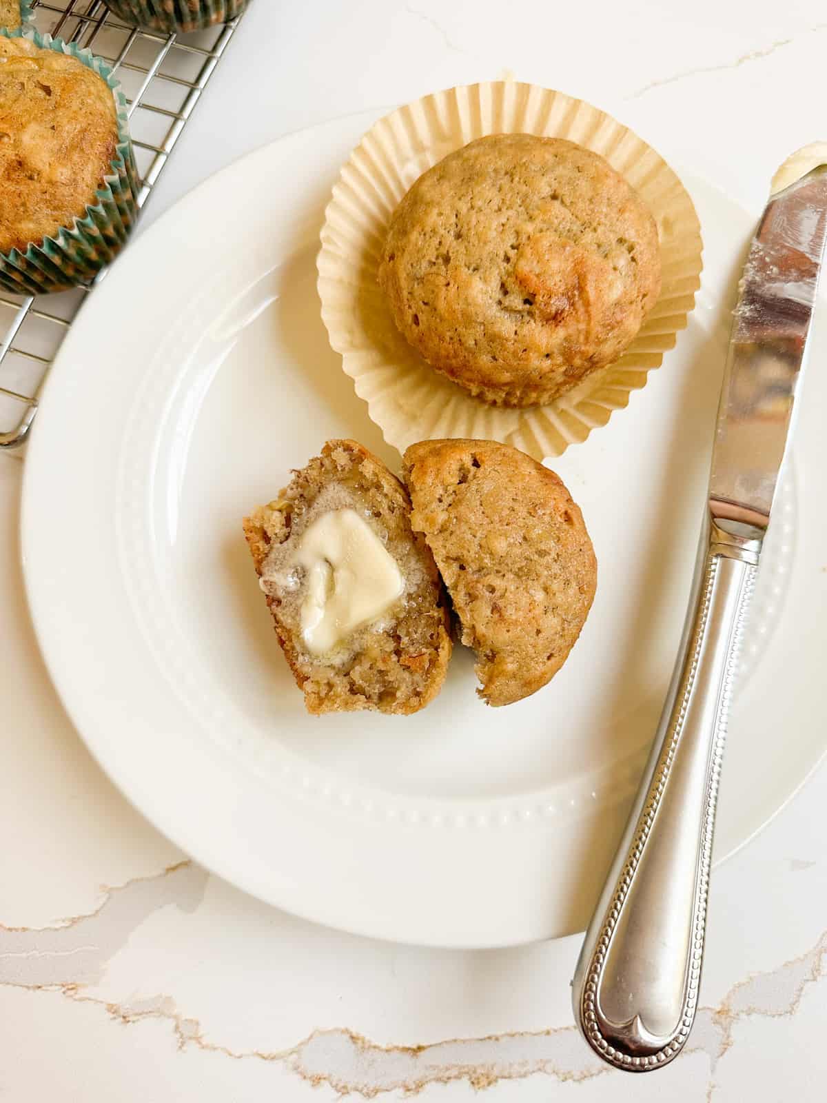Banana muffins on a plate with a knife and butter.