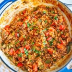Ground beef, bell peppers, rice and tomato sauce in a blue enamel skillet.