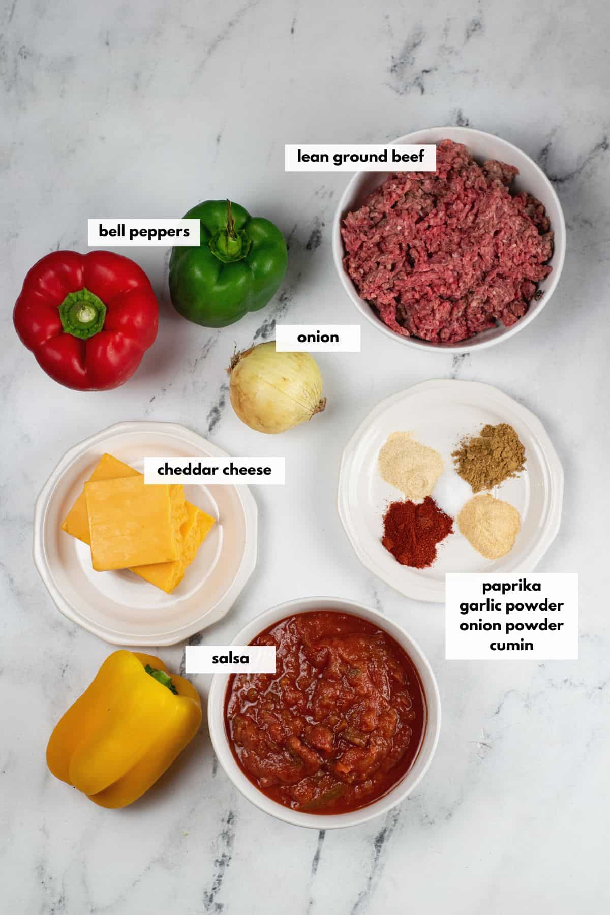 Ingredients to make taco stuffed peppers include beef, salsa, onion, cheddar cheese, garlic powder, onion powder, cumin and paprika.
