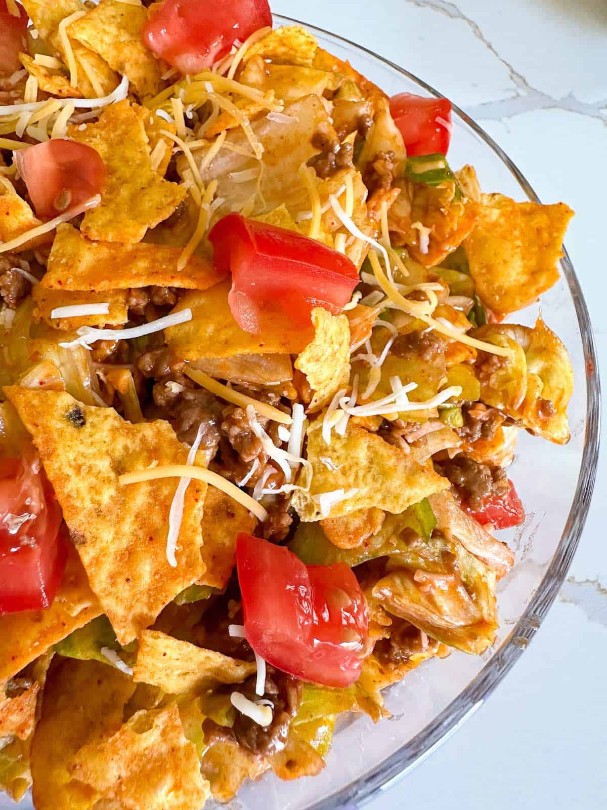 Taco salad topped with catalina dressing, crushed chips and cheese.
