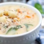 A bowl of creamy gnocchi soup with chicken and spinach.