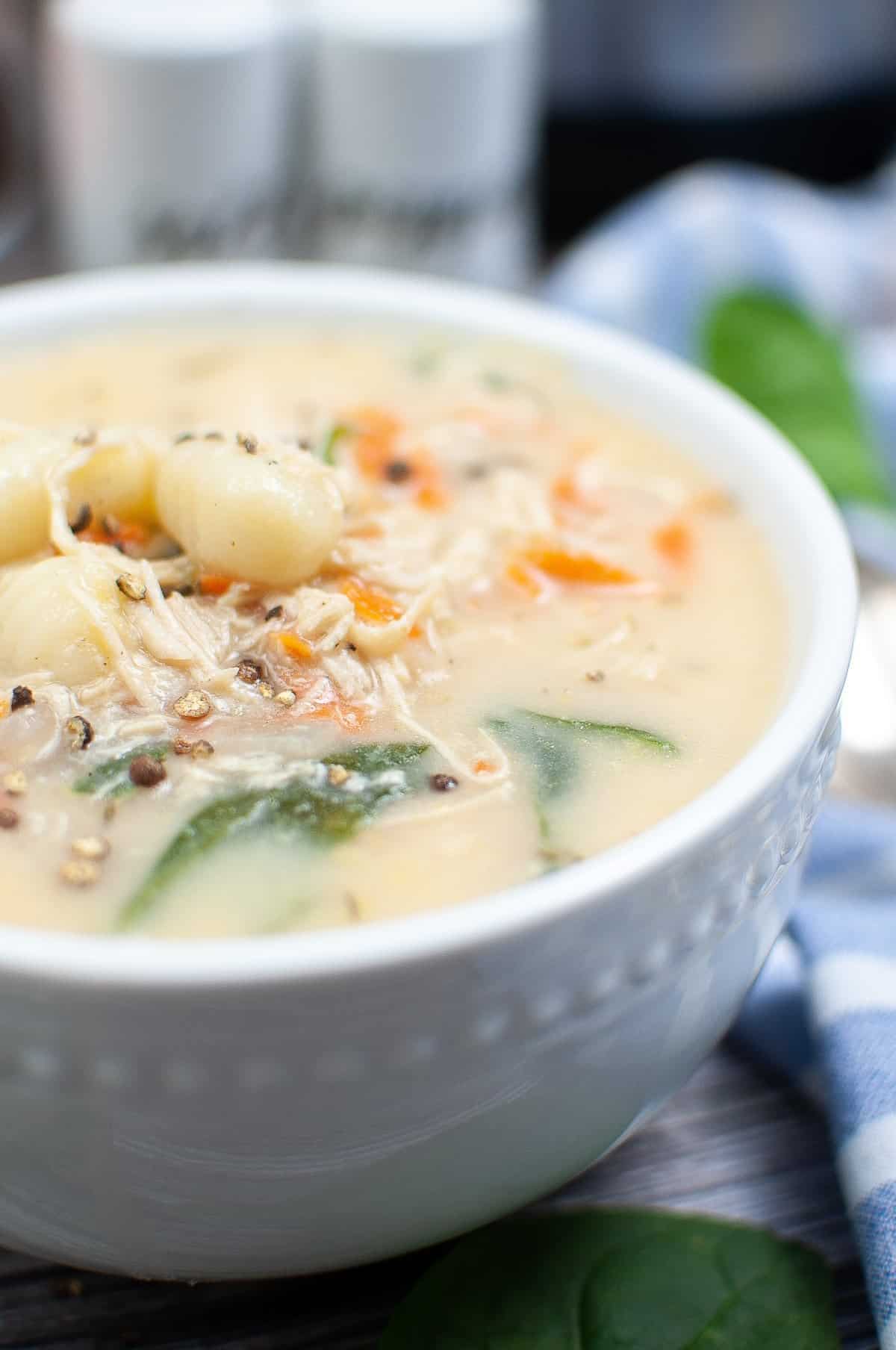 A bowl of creamy gnocchi soup with chicken and spinach.