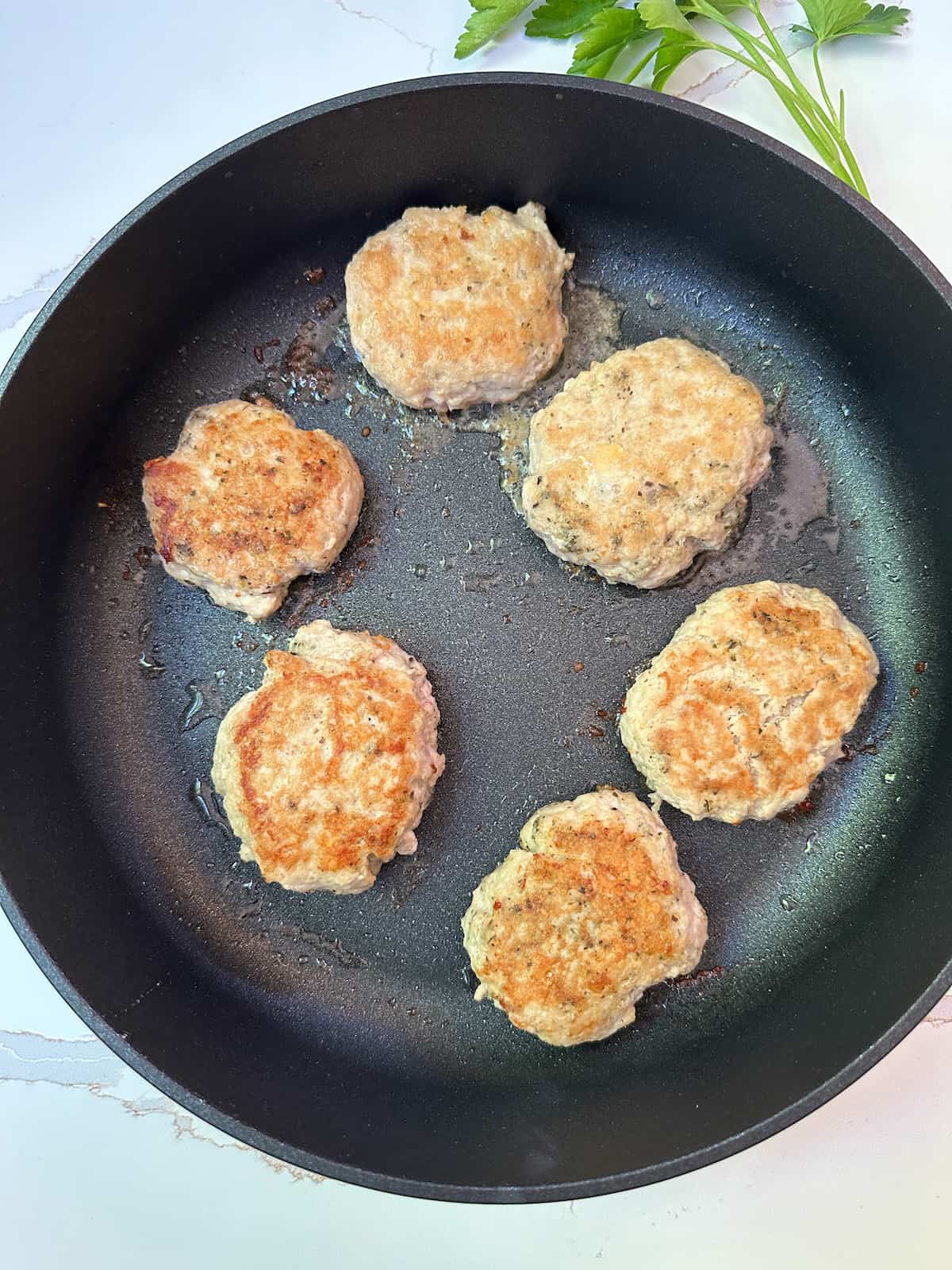 Cooked chicken patties in a large skillet.