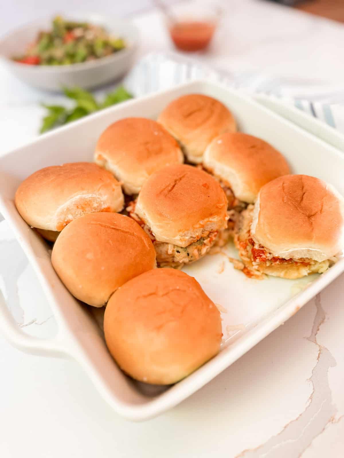 Baked chicken parm sliders in a square casserole dish.