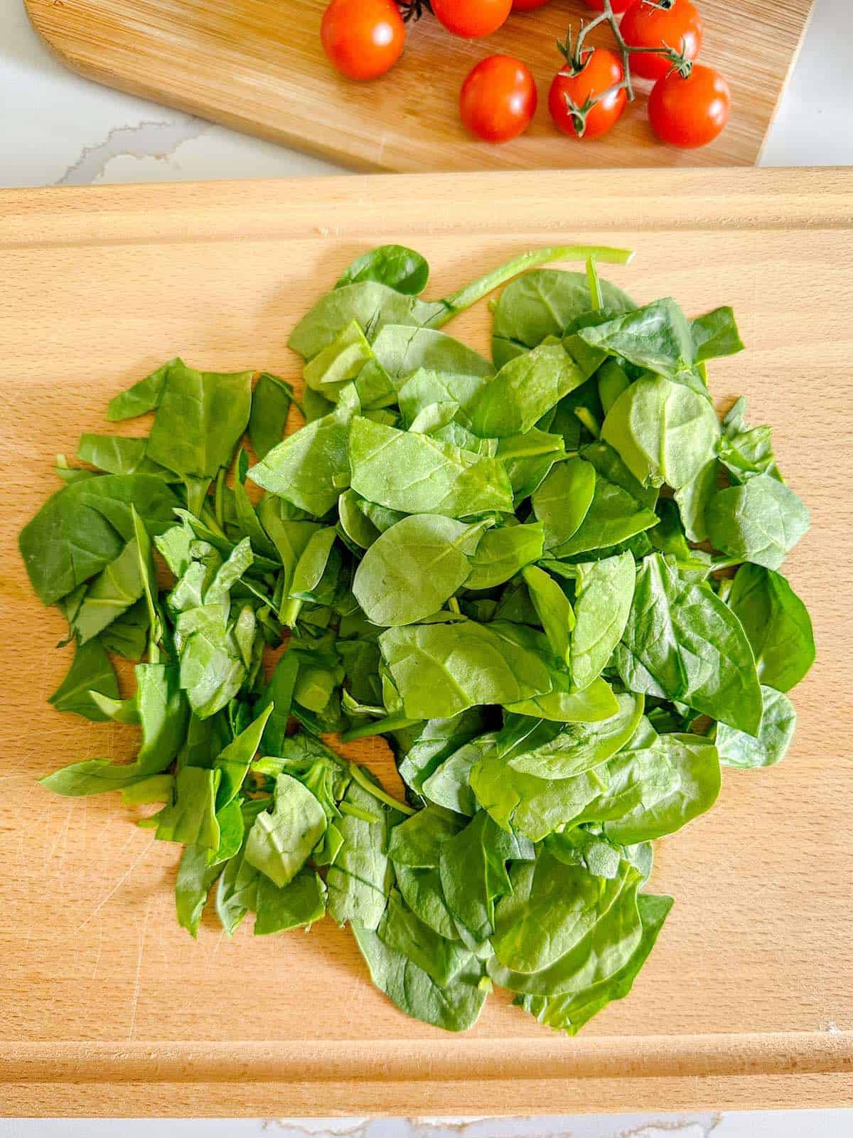 Chopped fresh spinach on a cutting board.