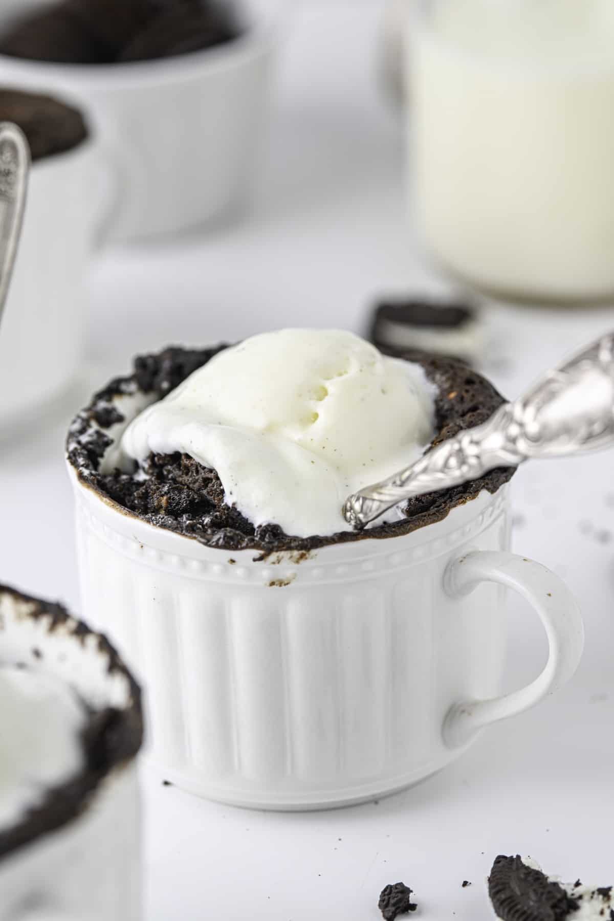 An oreo mug cake topped with a scoop of vanilla ice cream.