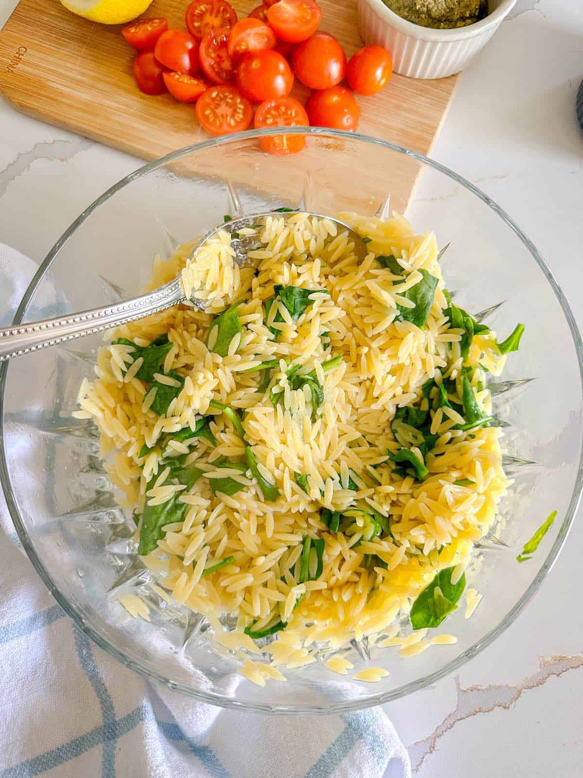 Cooked orzo pasta in a bowl with fresh spinach.