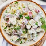 A plate of red potato salad topped with fresh dill.