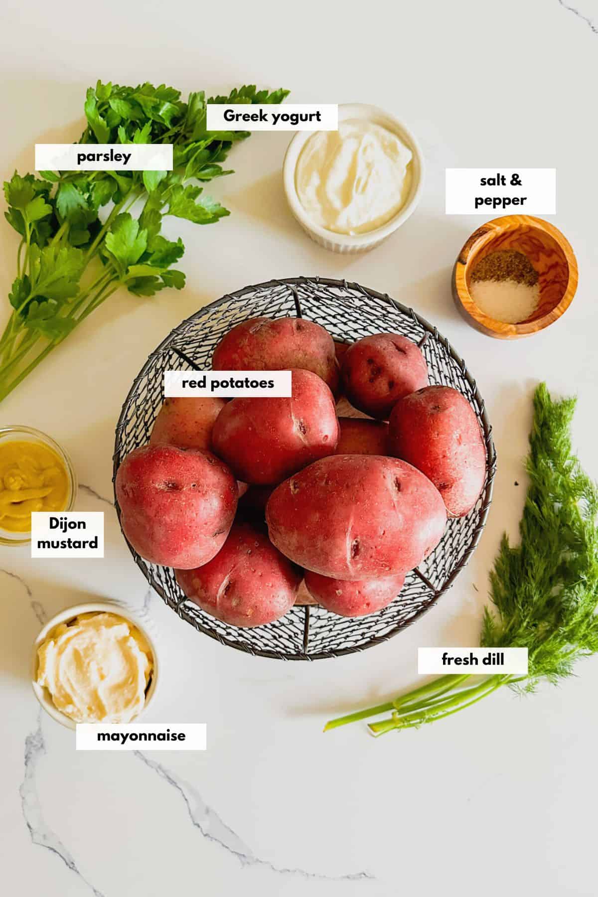 Ingredients to make fresh potato salad including red potatoes, parsley, fresh dill, Dijon mustard, Greek yogurt, sour cream, salt and pepper.