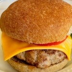 A juicy turkey burger on a bun topped with cheese and sliced tomato.