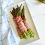Bundle of air fryer bacon wrapped asparagus on a plate.