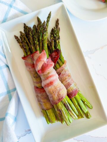 Bundle of air fryer bacon wrapped asparagus on a plate.