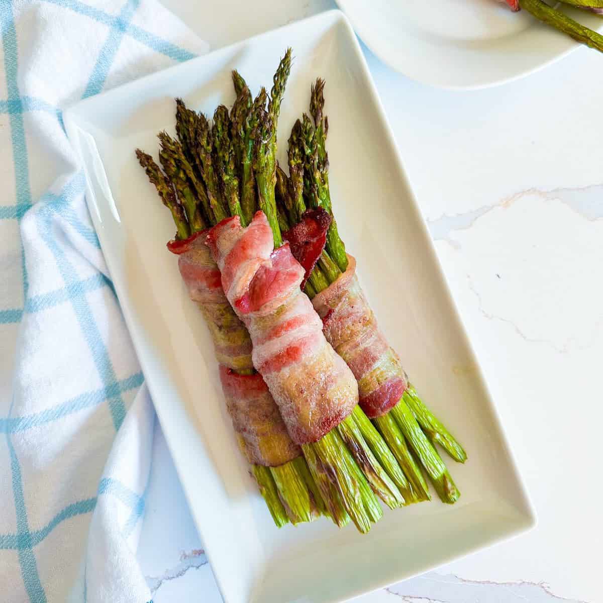 Bundle of air fryer bacon wrapped asparagus on a plate.