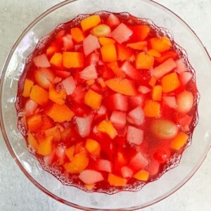 A bowl of jello with fruit cocktail in it.
