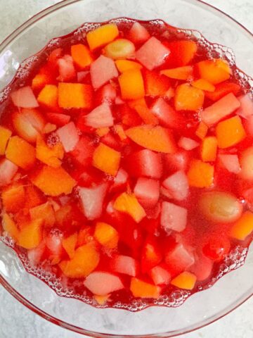 A bowl of jello with fruit cocktail in it.