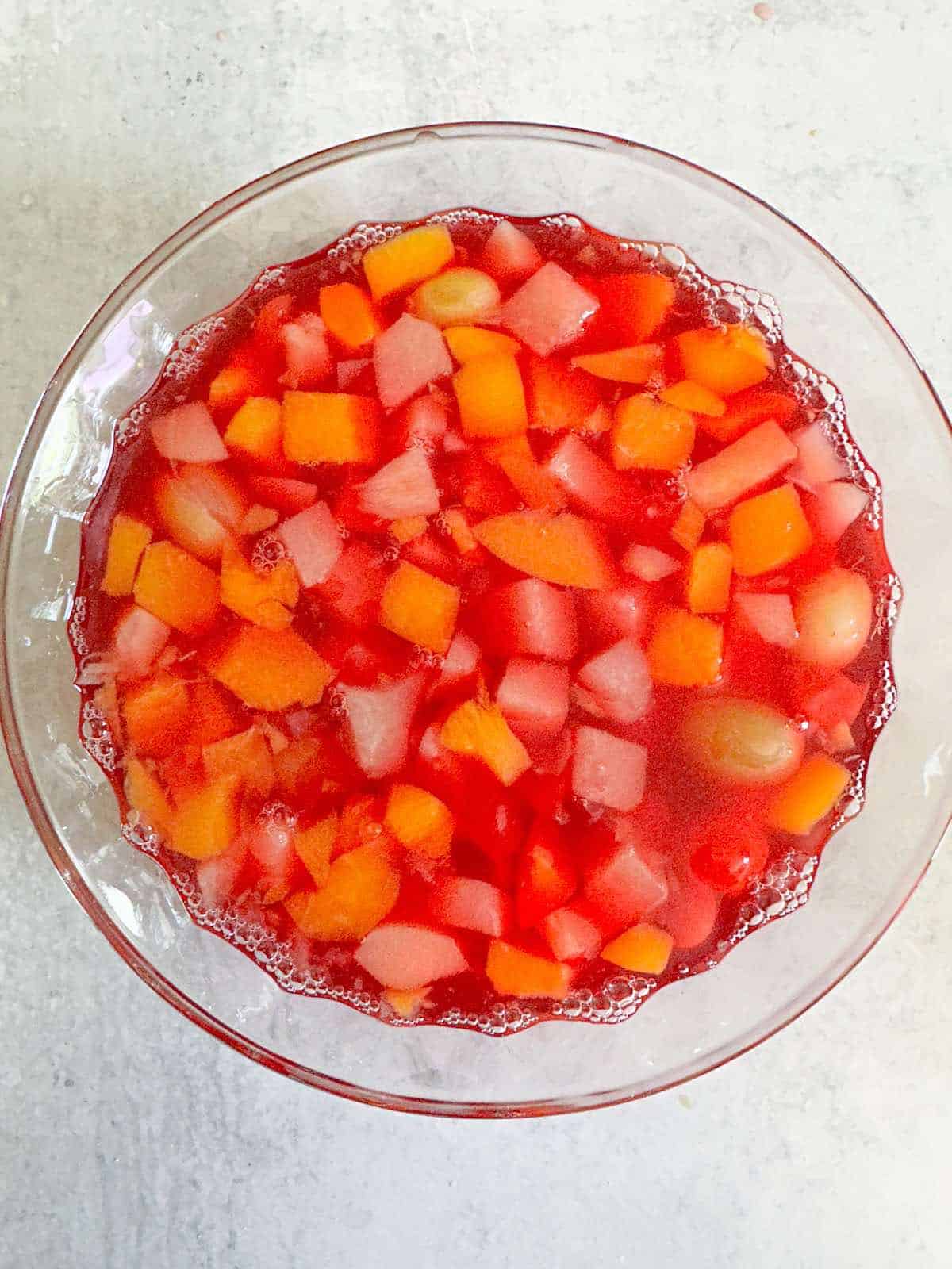 A bowl of fruit cocktail in jello after setting.