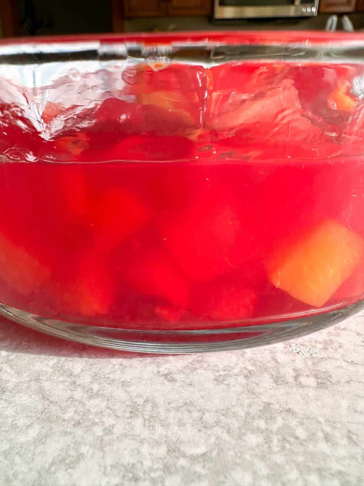 Stirred jello with fruit cocktail evenly dispersed. 