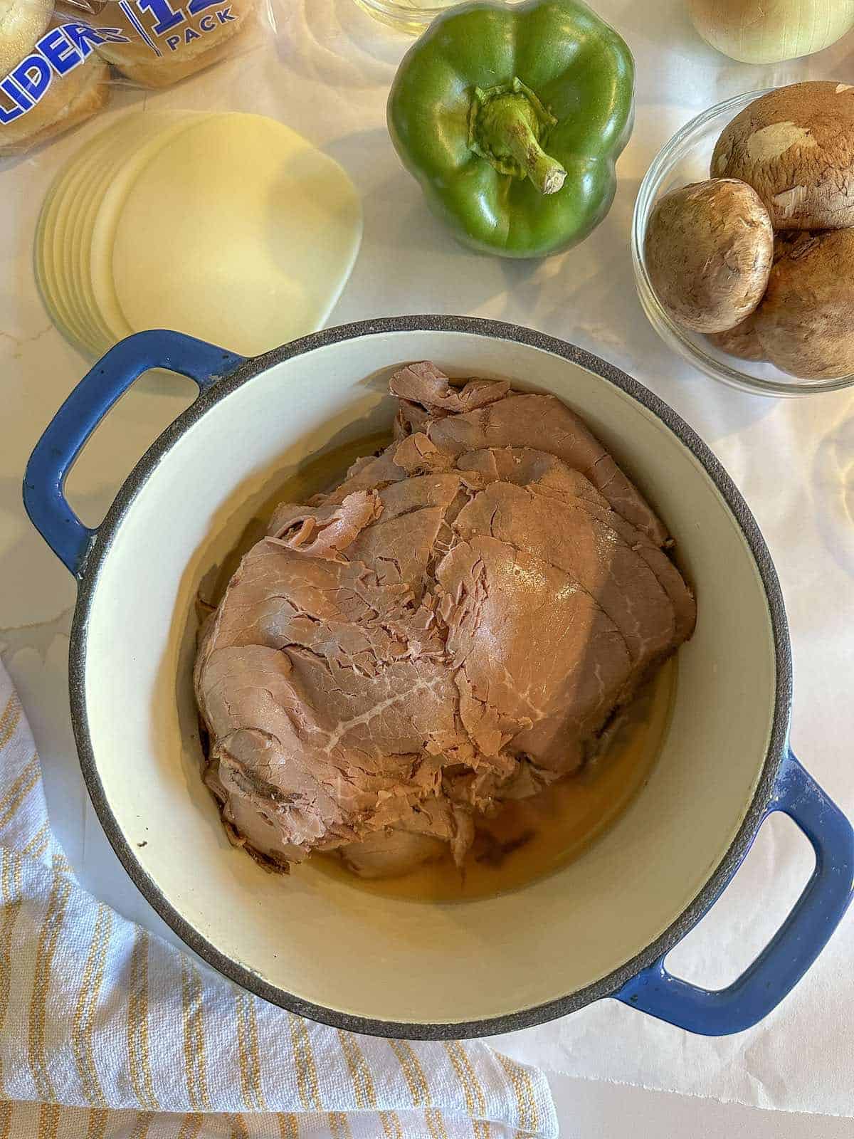 Beef broth and roast beef slices in a saucepan.