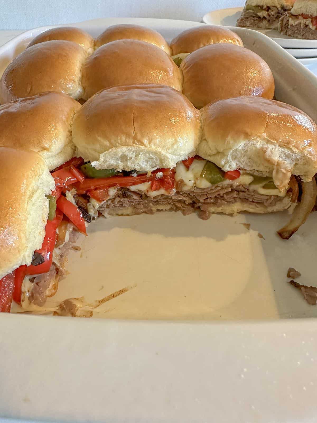 Baked Philly cheesesteak sliders in a pan.