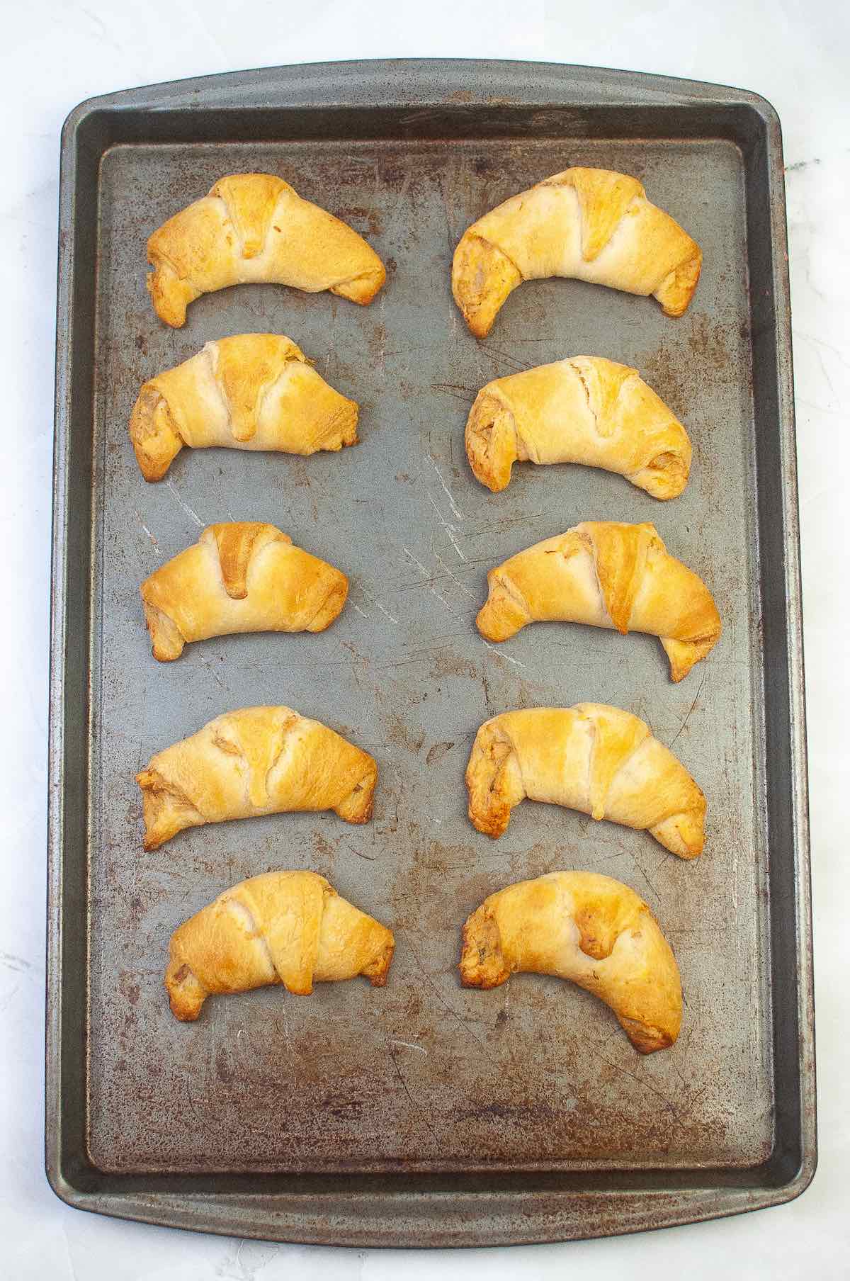 Baked crescent rolls on a cookie sheet.