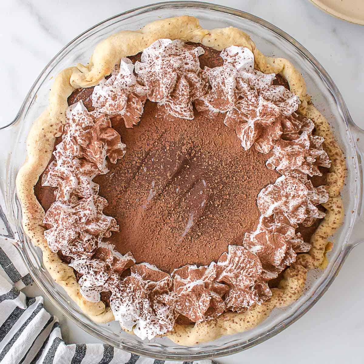 An old fashioned chocolate pie topped with whipped cream and chocolate shavings.