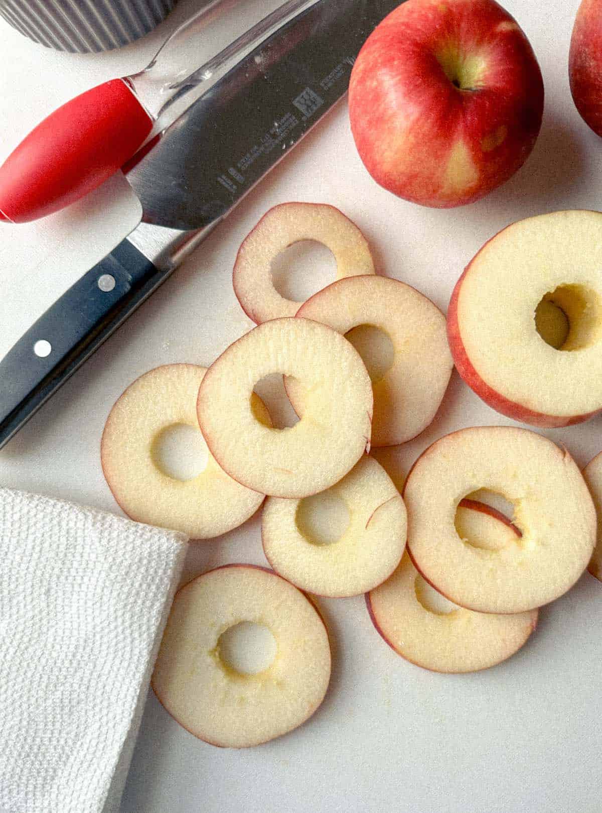 Cored apple slices on a cutting board with a knife.