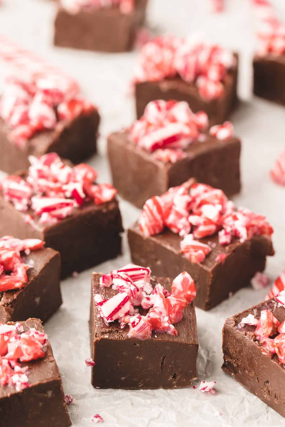 Peppermint fudge pieces on parchment paper, cut into squares.
