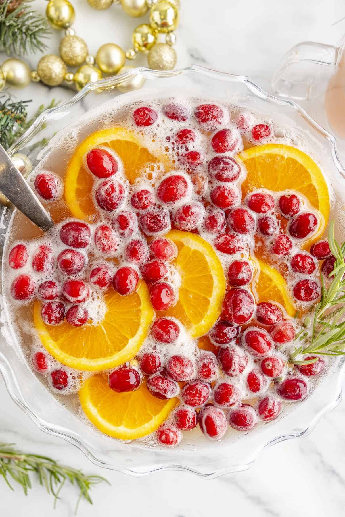 A Christmas holiday punch in a bowl, topped with cranberries and orange slices.
