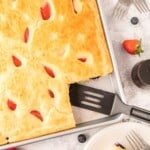 Sheet pan pancakes and berries with a slice cut out.