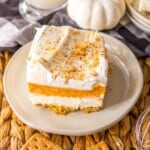 A slice of no bake pumpkin lush dessert on a plate topped with crumbled graham crackers.