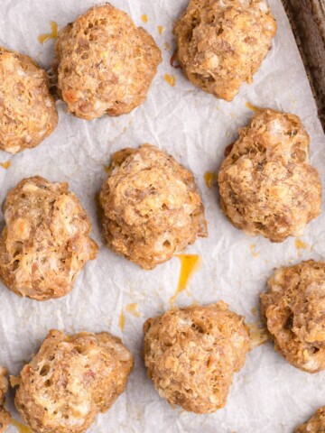 Baked sausage balls on a sheet pan lined with parchment paper.