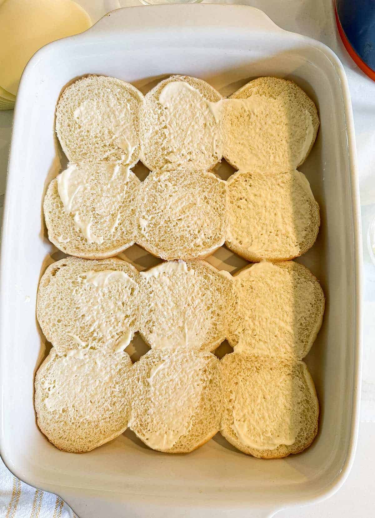 Mayo covered slider buns in a baking dish.