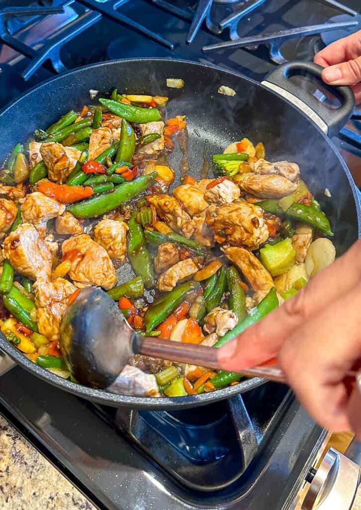 Pork tenderloin stir fry with sauce cooking in a pan.