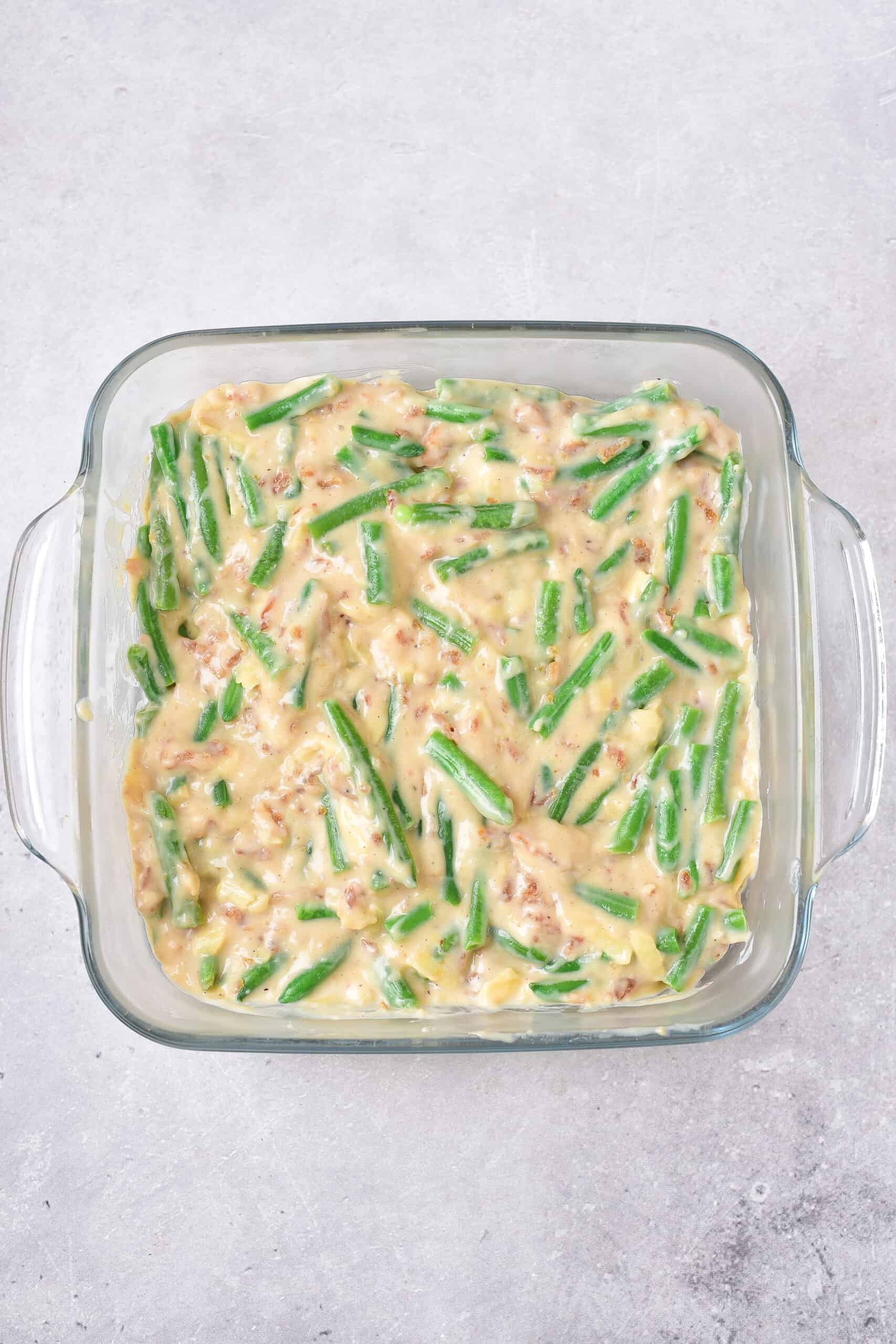 Unbaked green bean casserole in a square glass dish.