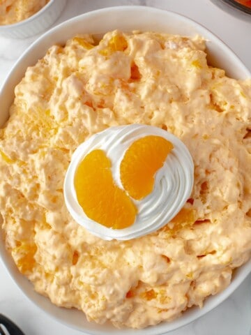 Creamy orange fluff salad is made with jello, whipped topping, and mandarin oranges.