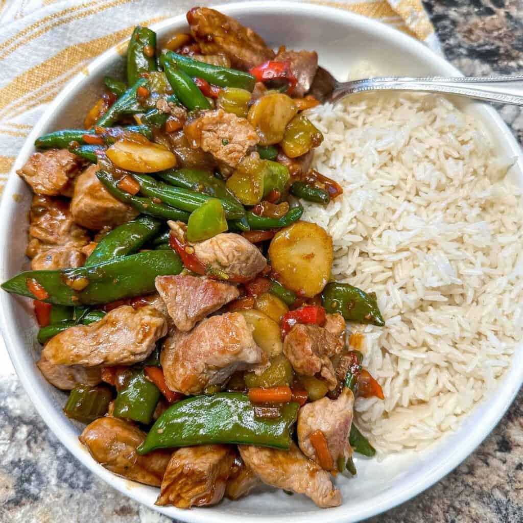 Pork stir fry in a bowl with rice.