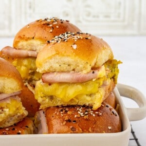 Ham, egg and cheese topped breakfast sliders with poppy seeds on top.