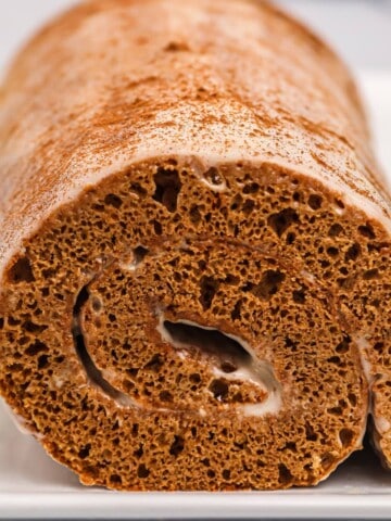 A rolled gingerbread cake with frosting in the middle.